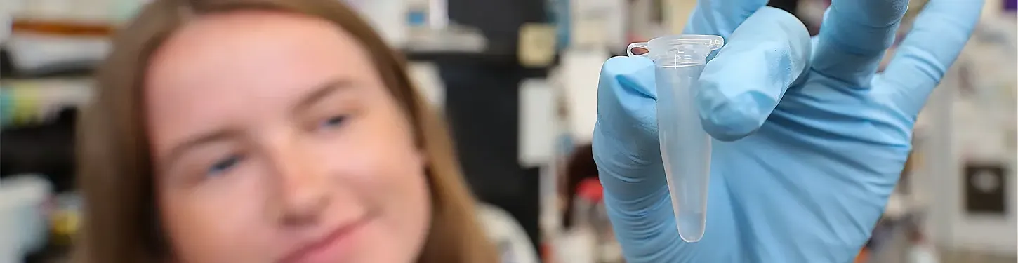 A student holds a vial in a gloved hand